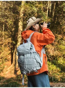 Hellblauer Nylon-Outdoor-Wanderrucksack, getragen von einer Reisenden im Wald