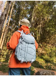 Rückansicht eines hellblauen Wanderrucksacks, getragen von einem Wanderer im Wald
