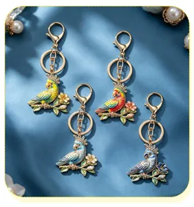 Macro detail view of four colorful enamel parrot keychains featuring rhinestone accents