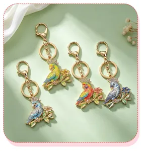 Detail view of four colorful enamel parrot keychains with elegant rhinestone accents.
