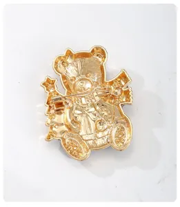 Vue arrière détaillée d'une broche ours de Noël dorée montrant l'attache épingle