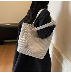 Detail of large beige corduroy tote bag showing texture and small coin purse attachment