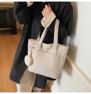 High-quality close-up of a large beige corduroy tote bag with matching coin purse