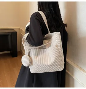 Detailed view of white corduroy tote bag showing its ribbed texture and small round pouch.