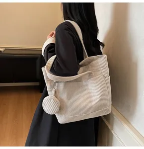 Vintage white corduroy tote bag with large capacity shown on a model in a minimal interior.