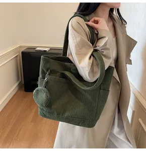 Close-up of a large green corduroy tote bag with a small coin purse charm