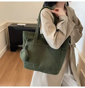 Model wearing a vintage dark green corduroy tote bag with a small matching coin purse