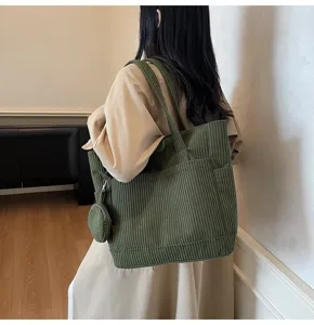 Back view of a woman wearing an olive green corduroy tote bag with a small matching pouch.