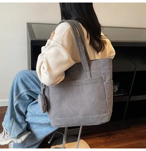 Stylish large capacity gray corduroy tote bag for students shown in a lifestyle campus setting