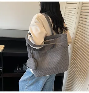 Fashionable grey corduroy tote bag carried by a model in a minimalist indoor setting