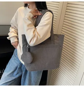 Detailed view of a grey corduroy tote bag featuring a matching round coin purse detail
