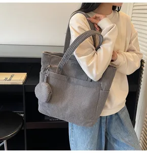Close-up of grey corduroy large-capacity tote bag with small round coin pouch attachment.