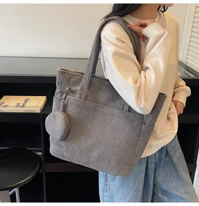 Large gray corduroy tote bag with matching coin purse held by model in shop