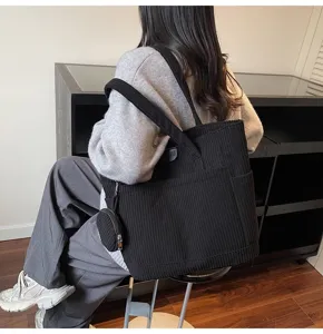 Stylish black large capacity corduroy tote bag with a small pouch in a lifestyle setting