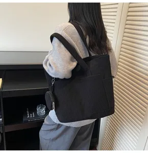 Detailed view of a black corduroy large capacity tote bag worn by a model