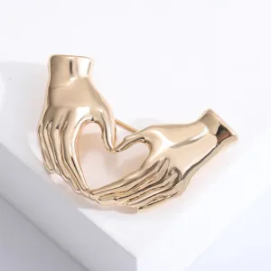 Detailansicht der eleganten goldenen Herz-Hand-Brosche mit einer polierten Vintage-Oberfläche.
