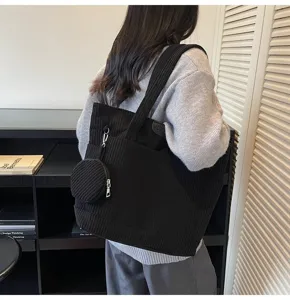 Woman carrying a large capacity black corduroy tote bag with a matching round pouch
