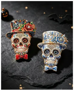 Detailed view of two Mexican Day of the Dead skull brooches with floral top hats.