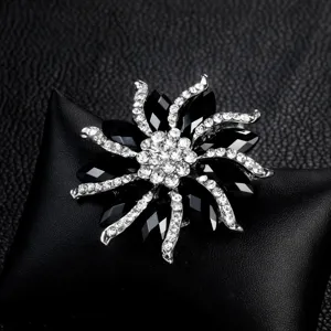 Elegant flower brooch with black and white crystals on black leather background