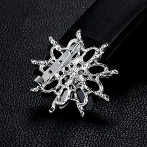 Detailed rear view of silver alloy flower brooch with safety pin clasp on black leather