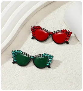 Detalle de dos elegantes broches con forma de gafas de sol con incrustaciones de diamantes rojos