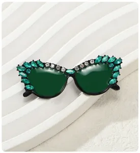 Vista macro de un broche con forma de gafas de sol y diamantes de imitación verdes
