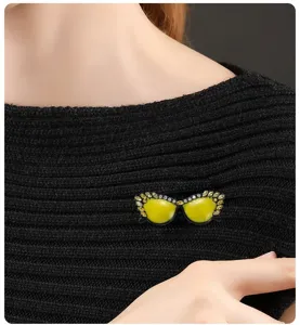Primer plano de un creativo broche de gafas de sol amarillas con diamantes de imitación.