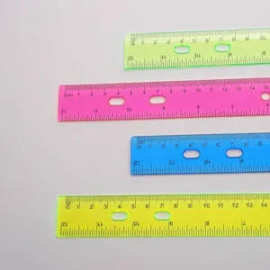 Primer plano de cuatro reglas de plástico de colores translúcidos con escalas métricas