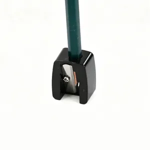 Macro view of a black mini single-hole cosmetic pencil sharpener with a green pencil