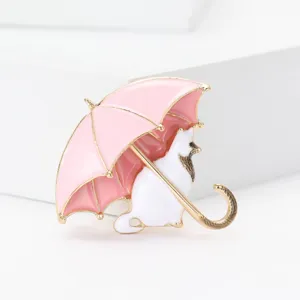 Primo piano di una graziosa spilla giapponese in smalto rosa con ombrello e gatto