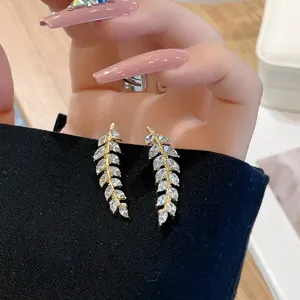Close-up detail of sparkling gold-tone wheat ear row earrings with marquise-cut stones.