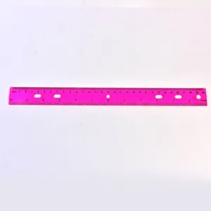 Gros plan sur une règle en plastique rose de 30 cm avec 6 trous et double graduation