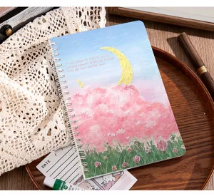 Primer plano de cuaderno de espiral A5 con portada estética de nubes rosas al óleo.
