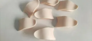 Close-up of multiple pale pink silicone eyelash applicator tools on white background.