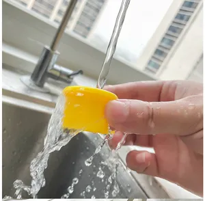 Close-up of vibrant yellow silicone wine bottle cap being rinsed under running tap water.