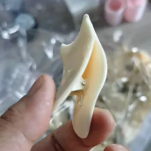 Macro detail of an ergonomic cream-colored plastic eyelash applicator tool for eye makeup