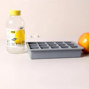 Side view of a fifteen-compartment gray silicone ice cube tray placed on a plain white surface