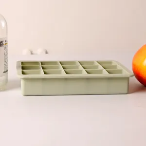Side view of a 15-grid sage green silicone ice cube tray on a clean white table.