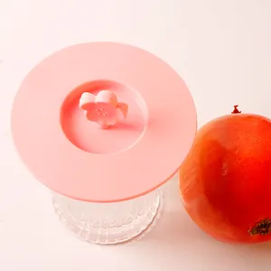 Detailed macro view of a pink flower shaped silicone cup lid on a clear ribbed glass cup.