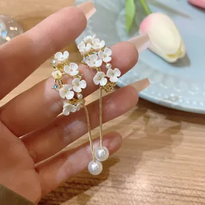 Dettaglio degli orecchini floreali in stile francese con pendenti di perle e catena dorata.