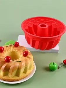 Close-up detail of red silicone bundt cake mold with freshly baked cake and cherries