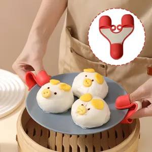 Détail des pinces à bol en silicone rouge à trois doigts soulevant une assiette