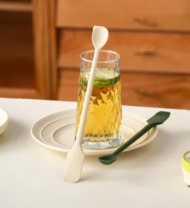 Detail view of double-ended silicone jam spatulas in cream and green colors on a table