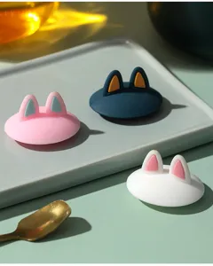 Three colorful silicone cup lids with cute cat ear designs presented on a modern tray