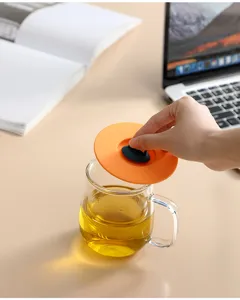 Detail shot of a flexible orange silicone cup lid being placed on a glass mug