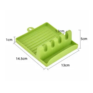 Green plastic kitchen spoon rest and pot lid holder with multiple slots and oil drainage tray.