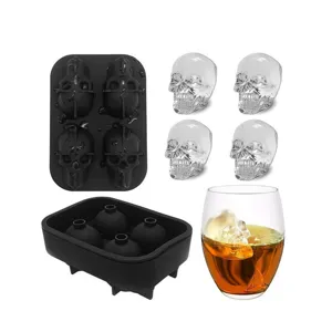 Detailed view of 4-cell silicone skull ice mold with clear ice skulls and a whiskey glass.