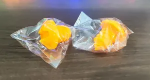 Detailansicht von zwei orangefarbenen Silikon-Weinverschlüssen in Kunststoffverpackung.