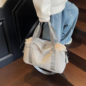 Close-up of a large grey waterproof duffle bag carried by a model on wooden stairs