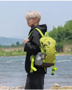 Uomo che indossa uno zaino da trekking verde lime vicino a un fiume panoramico all'aperto